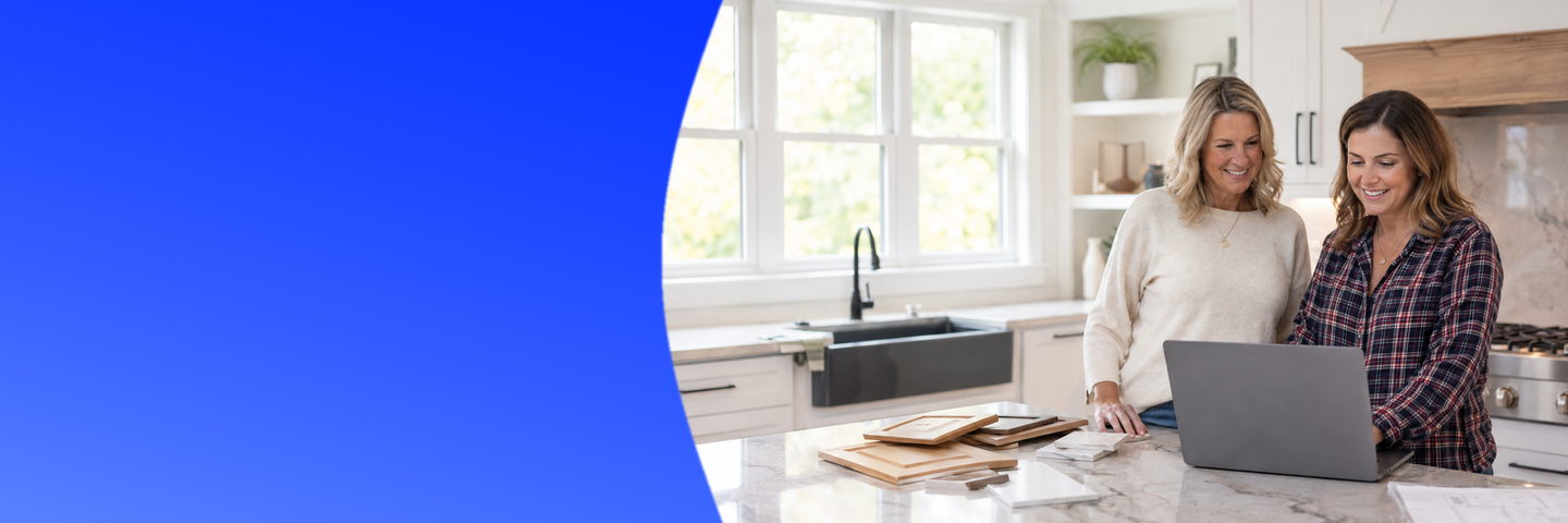 A contractor and a homeowner looking at a laptop in a bright kitchen